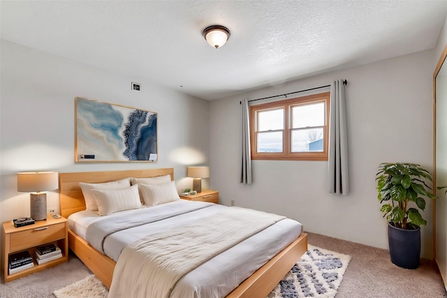 bedroom with a textured ceiling and light carpet