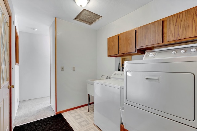 clothes washing area with cabinets and washing machine and dryer