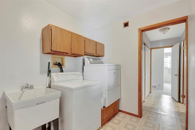 clothes washing area featuring sink, cabinets, and washer and clothes dryer