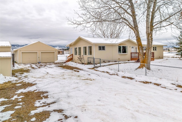 snow covered rear of property with a garage and an outdoor structure