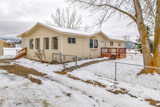 snow covered back of property with a deck