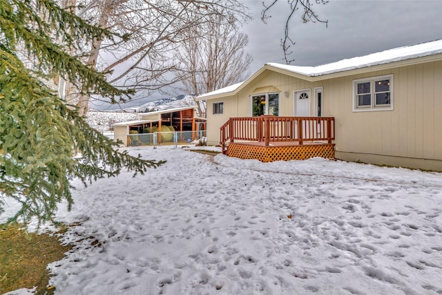 snow covered rear of property with a wooden deck