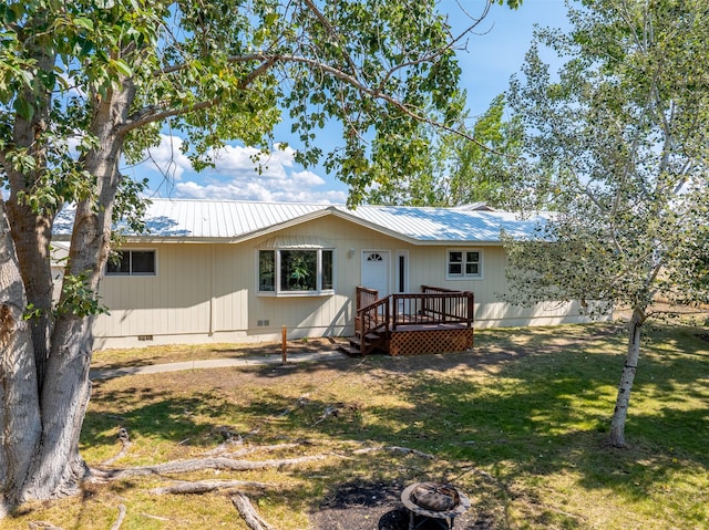 rear view of house featuring a wooden deck and a lawn