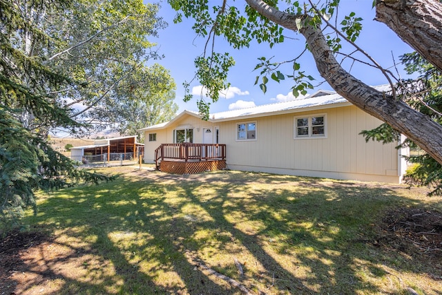 rear view of property featuring a deck, a carport, and a lawn