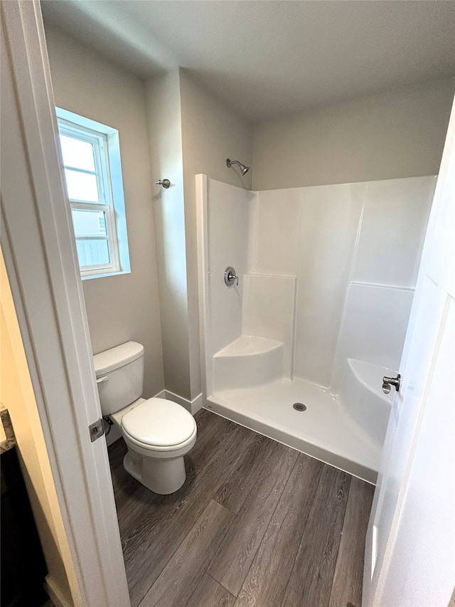 bathroom featuring toilet, a shower, and hardwood / wood-style flooring