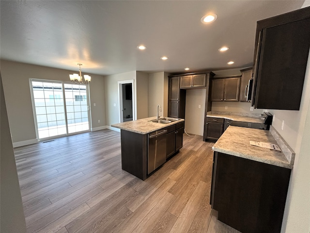 kitchen with stainless steel appliances, a center island with sink, a notable chandelier, light hardwood / wood-style floors, and sink