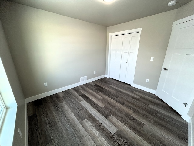 unfurnished bedroom featuring dark hardwood / wood-style flooring and a closet