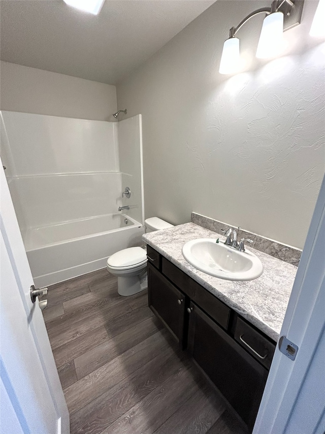 full bathroom featuring toilet, hardwood / wood-style flooring, washtub / shower combination, and vanity