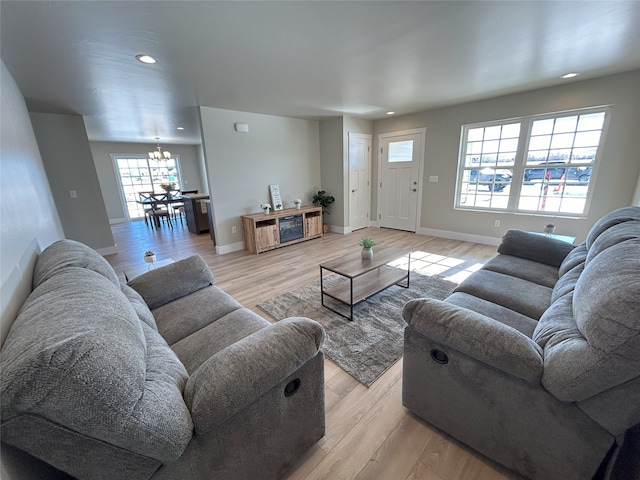 living room with light hardwood / wood-style floors and an inviting chandelier