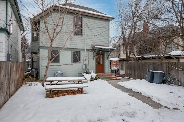 snow covered house featuring central AC unit