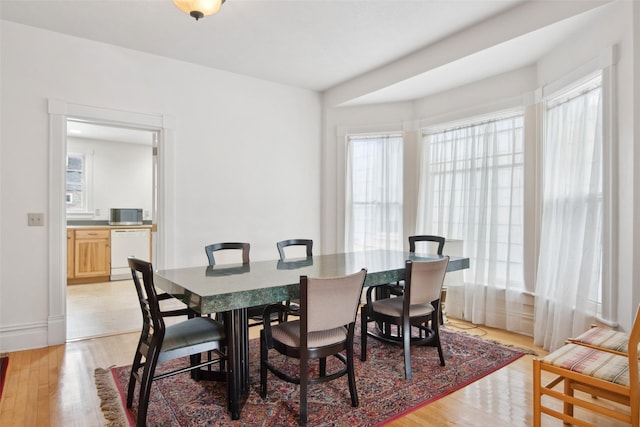 dining area with a wealth of natural light and light hardwood / wood-style flooring