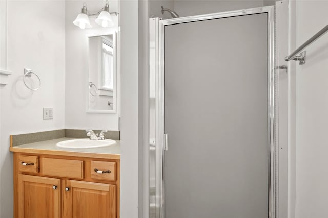 bathroom featuring a shower with door and vanity