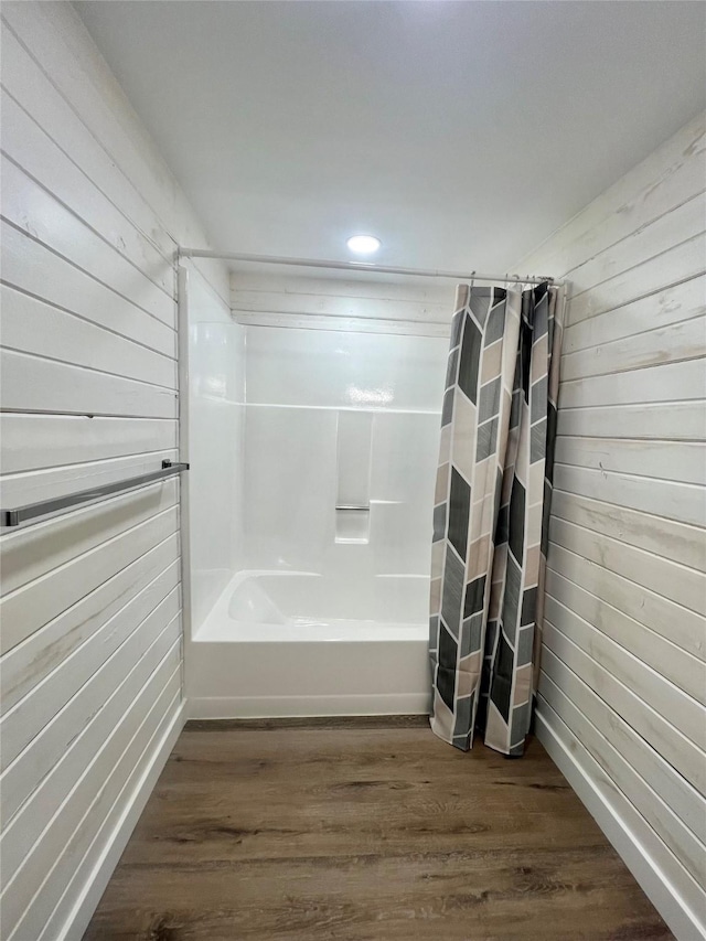 bathroom with shower / bath combination with curtain, wood walls, and wood-type flooring