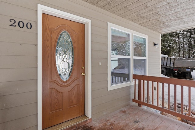 snow covered property entrance with covered porch