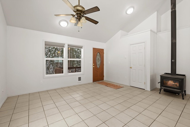 foyer entrance with ceiling fan, lofted ceiling, a wood stove, and light tile patterned floors