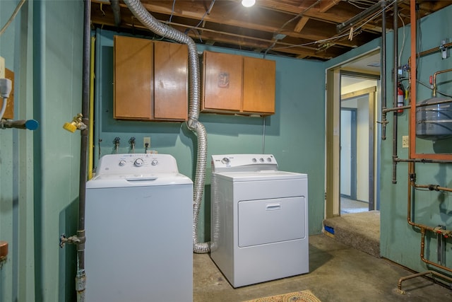 clothes washing area featuring washer and dryer and cabinets