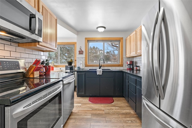 kitchen featuring sink, stainless steel appliances, light brown cabinetry, and decorative backsplash