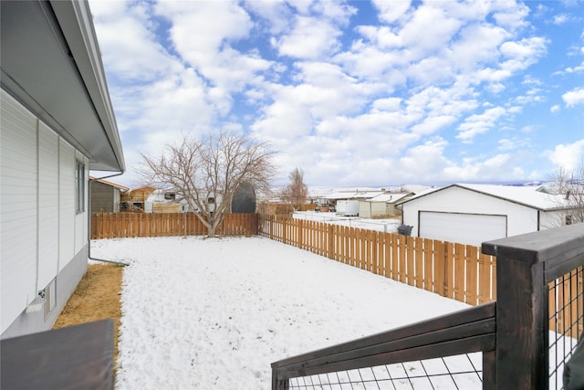 snowy yard with a garage and an outbuilding