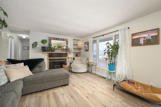 607 Oregon St, Deer Lodge, MT 59722 - living area featuring wood finished floors, a textured ceiling, a fireplace, and baseboards