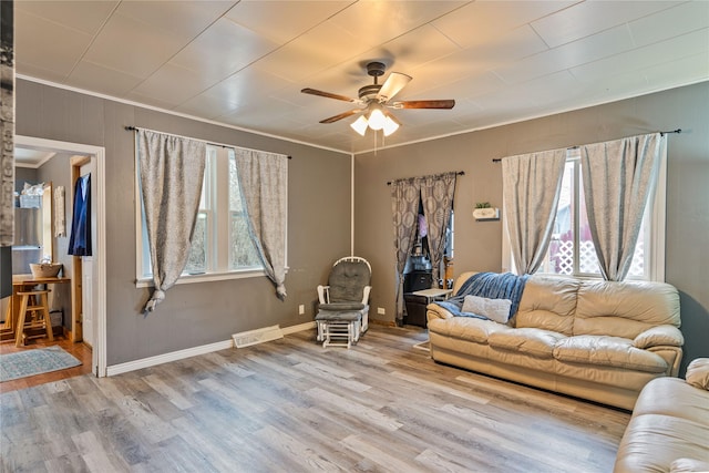 living room with light wood-type flooring, ceiling fan, and ornamental molding