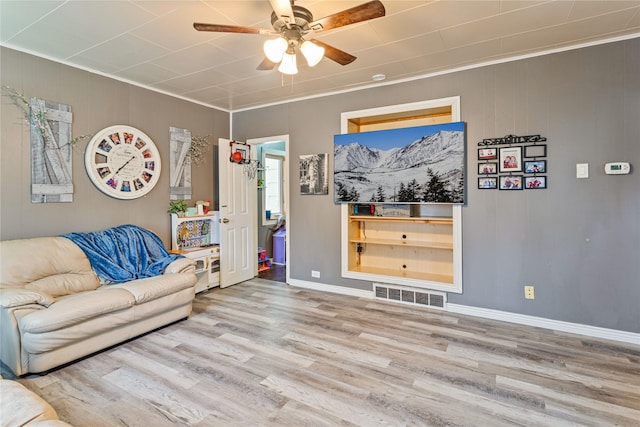 living room with ornamental molding, ceiling fan, and light wood-type flooring