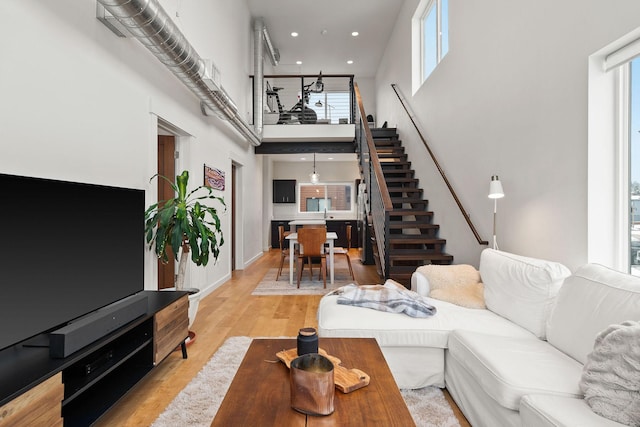 living room featuring a towering ceiling and light wood-type flooring