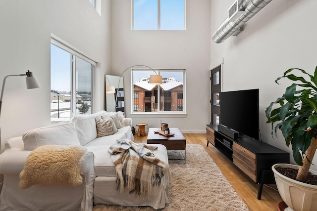 living room with a towering ceiling and light hardwood / wood-style flooring