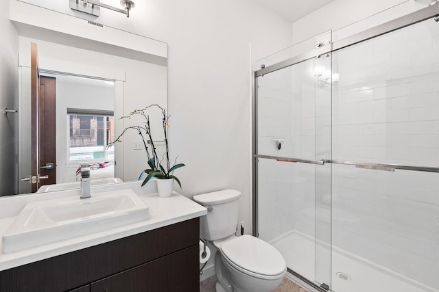 bathroom featuring vanity, a shower with shower door, and toilet