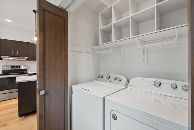 laundry room featuring washing machine and dryer and light hardwood / wood-style flooring