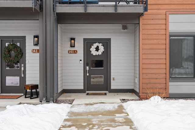 snow covered property entrance featuring a balcony