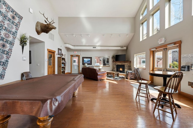 rec room with light hardwood / wood-style flooring, track lighting, billiards, and a towering ceiling