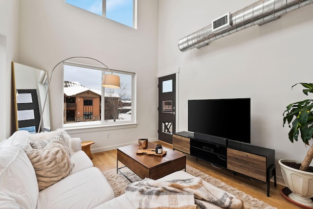 living room with a towering ceiling and light hardwood / wood-style floors