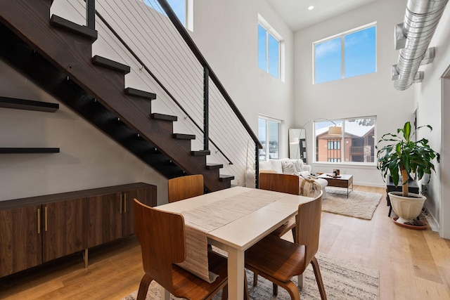 dining space featuring a towering ceiling and light hardwood / wood-style floors