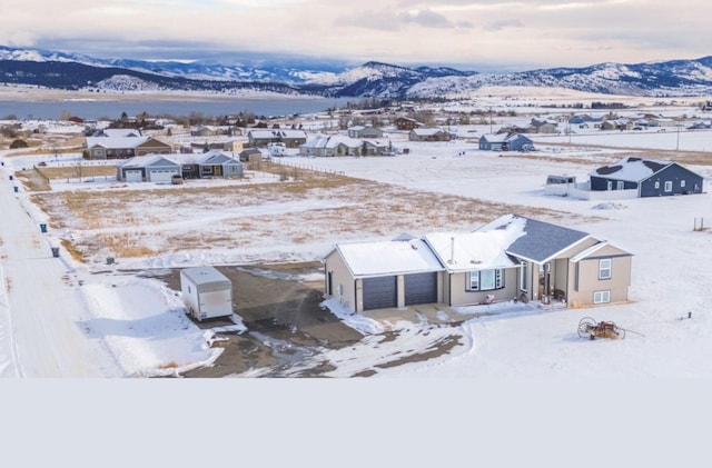 snowy aerial view featuring a mountain view and a residential view