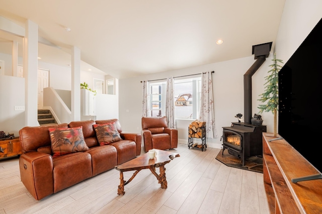 living room with a wood stove, recessed lighting, stairs, vaulted ceiling, and light wood-type flooring