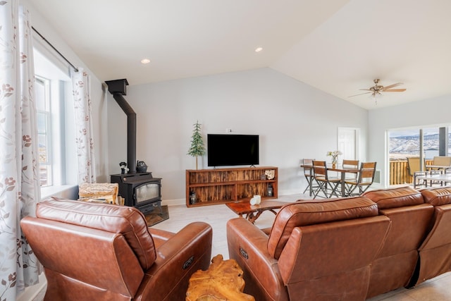 living area featuring ceiling fan, vaulted ceiling, light wood-style flooring, recessed lighting, and a wood stove