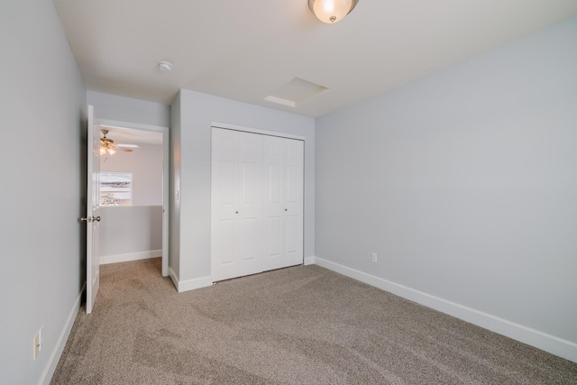 unfurnished bedroom featuring a closet, baseboards, carpet, and attic access