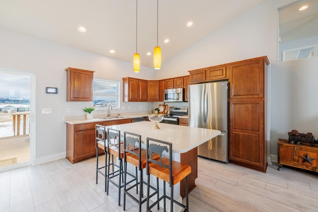 kitchen featuring a kitchen bar, light countertops, appliances with stainless steel finishes, and a sink