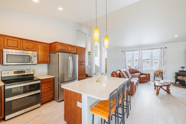 kitchen with open floor plan, stainless steel appliances, a wood stove, and light countertops