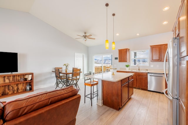 kitchen featuring open floor plan, a kitchen bar, lofted ceiling, light countertops, and stainless steel appliances