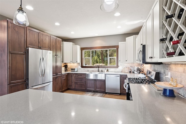 kitchen with stainless steel appliances, white cabinetry, tasteful backsplash, and hanging light fixtures