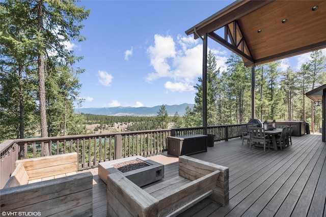 deck featuring a hot tub, an outdoor fire pit, and a mountain view