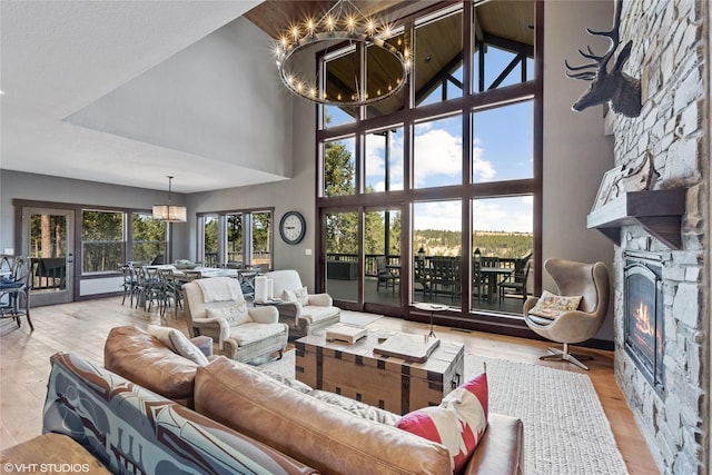 living room with a fireplace, high vaulted ceiling, light hardwood / wood-style flooring, and a chandelier