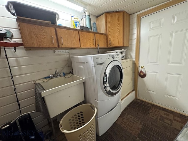 washroom featuring sink, cabinets, washer and clothes dryer, and wood walls