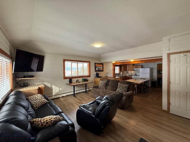 living room with wooden walls, baseboard heating, and dark hardwood / wood-style floors