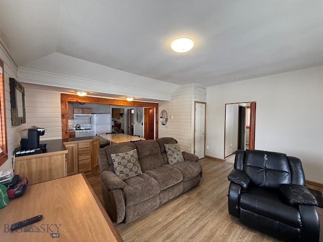 living room featuring wooden walls, vaulted ceiling, and wood-type flooring