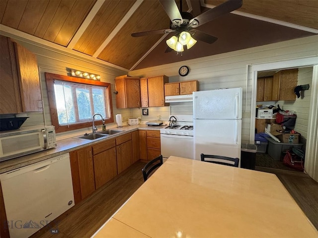 kitchen featuring sink, white appliances, wood walls, and lofted ceiling