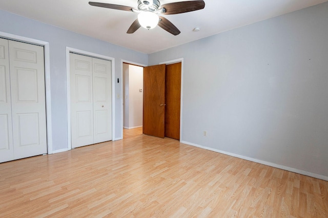 unfurnished bedroom featuring two closets, ceiling fan, and light wood-type flooring