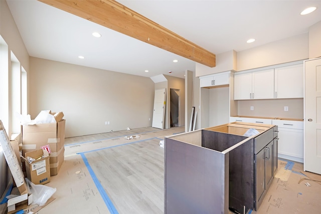 kitchen with white cabinetry, a center island, beamed ceiling, and dark brown cabinetry