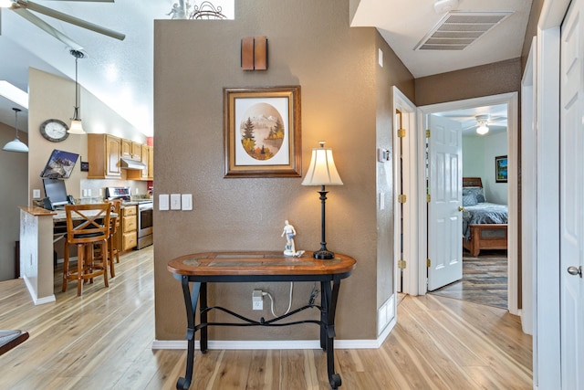 hallway with vaulted ceiling and light hardwood / wood-style flooring